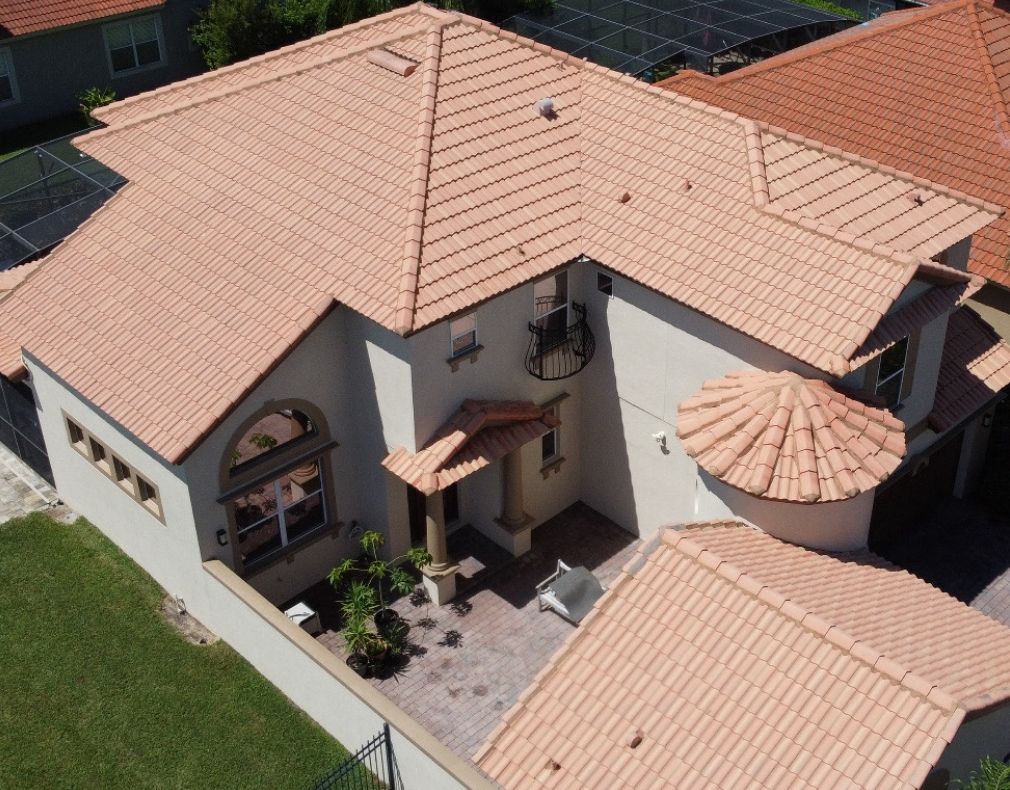Aerial view of stucco home with clean orange tile roof and paved patio in Central Florida