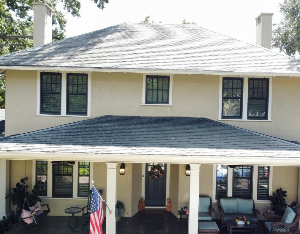 Clean two-story stucco home with dark shingle roof and American flag in Central Florida