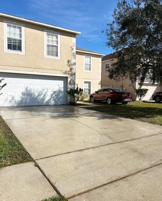 Clean concrete driveway in front of two-story stucco home after pressure washing
