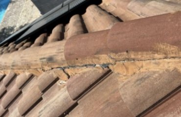 Close-up of cracked mortar on clay tile roof ridge showing need for maintenance