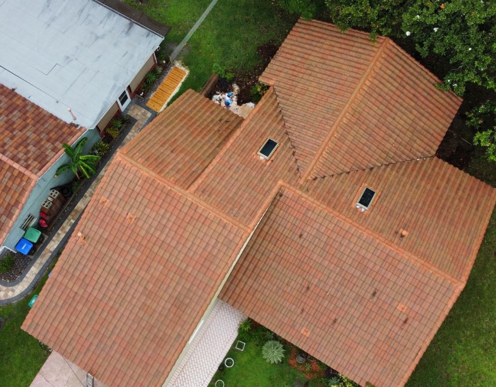 Aerial view of tile roof cleaning in progress with crew visible on Florida home