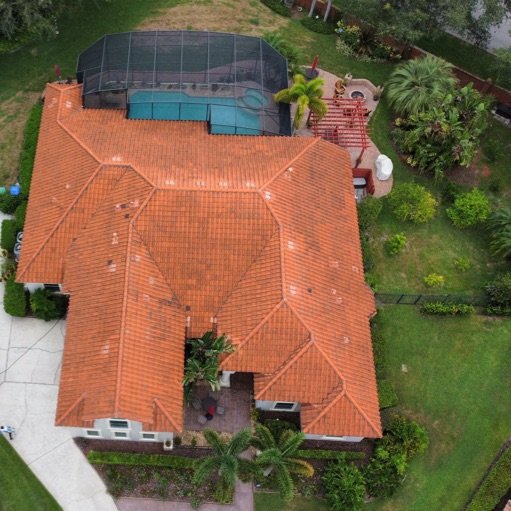 Aerial view of terracotta tile roof with algae and dark stains before professional cleaning